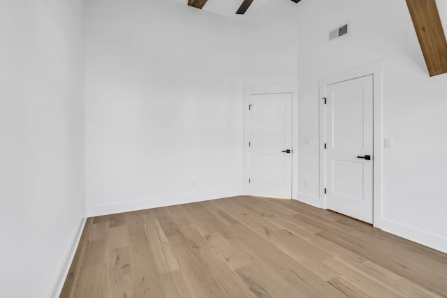 spare room with a towering ceiling, light hardwood / wood-style floors, and ceiling fan