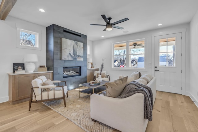 living room with a wealth of natural light, a large fireplace, and light wood-type flooring