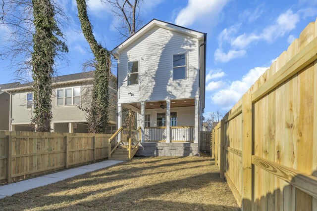 rear view of house featuring ceiling fan, a porch, and a lawn