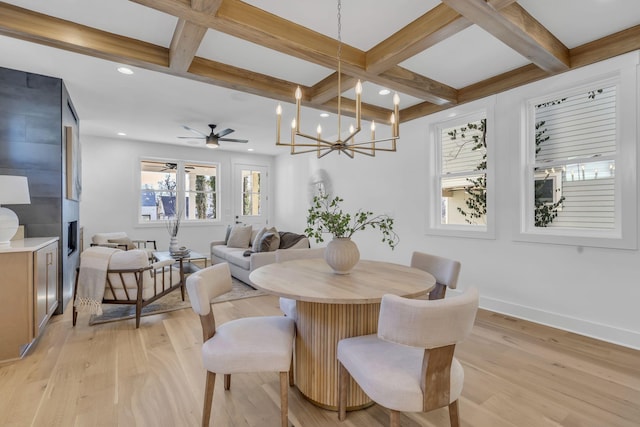 dining space with coffered ceiling, light hardwood / wood-style flooring, a large fireplace, beamed ceiling, and ceiling fan with notable chandelier