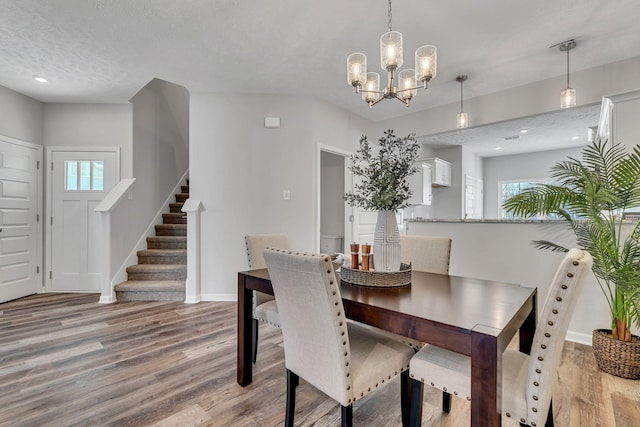 dining area with light wood-type flooring, a chandelier, and a textured ceiling