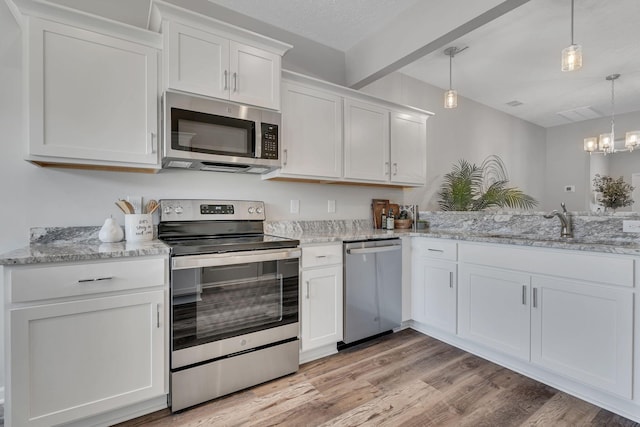 kitchen with stainless steel appliances, hanging light fixtures, light hardwood / wood-style floors, sink, and white cabinets