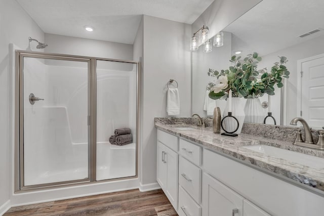 bathroom with a textured ceiling, vanity, walk in shower, and hardwood / wood-style floors