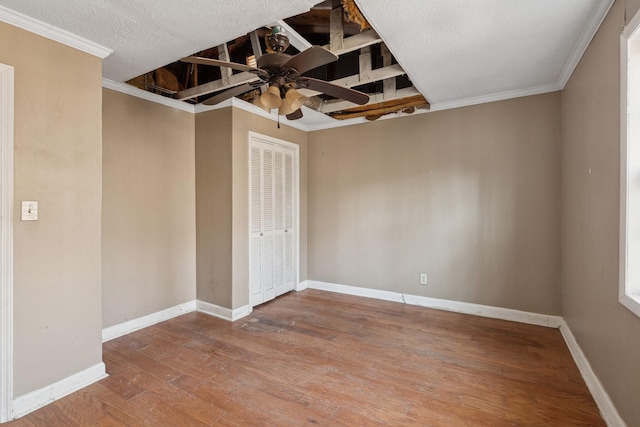 empty room featuring a textured ceiling, wood-type flooring, ornamental molding, and ceiling fan