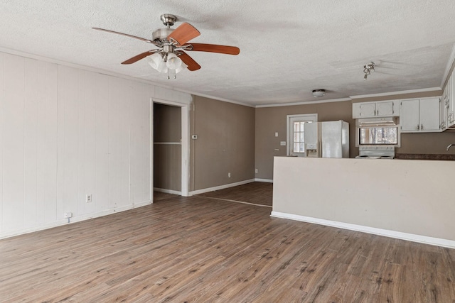 unfurnished living room featuring ceiling fan, ornamental molding, hardwood / wood-style floors, and a textured ceiling