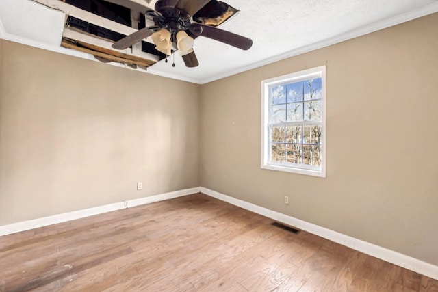 empty room featuring a textured ceiling, ornamental molding, light hardwood / wood-style floors, and ceiling fan