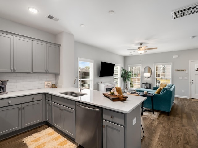 kitchen with dark wood-type flooring, sink, stainless steel dishwasher, gray cabinets, and kitchen peninsula