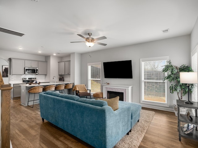 living room featuring hardwood / wood-style flooring, ceiling fan, and sink