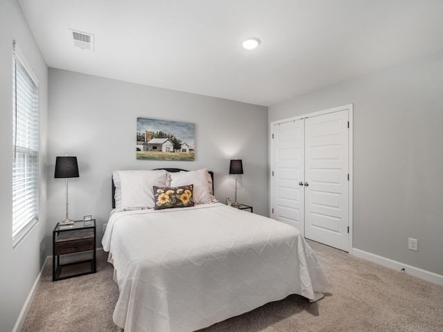 bedroom featuring multiple windows, a closet, and light carpet