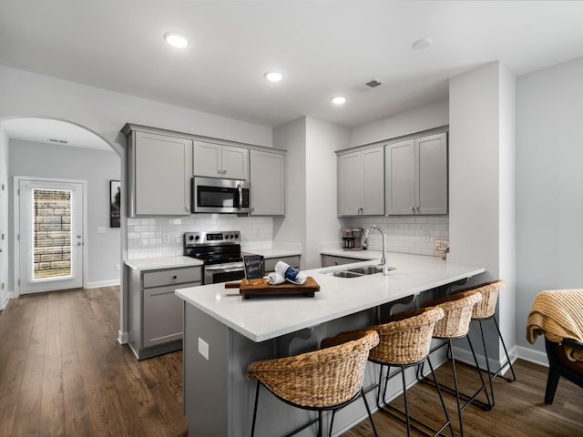 kitchen with sink, a breakfast bar area, gray cabinetry, kitchen peninsula, and stainless steel appliances