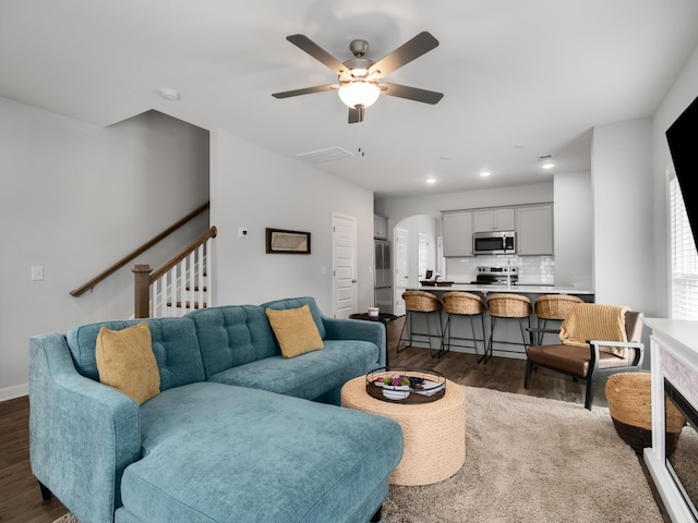 living room with ceiling fan and dark hardwood / wood-style flooring