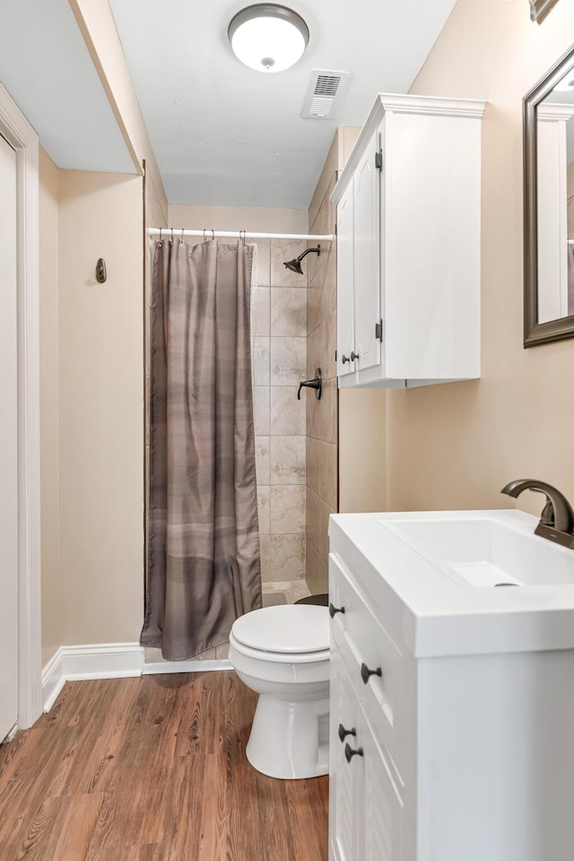 bathroom featuring vanity, curtained shower, wood-type flooring, and toilet