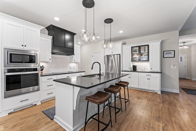 kitchen with sink, a breakfast bar area, hanging light fixtures, a center island with sink, and appliances with stainless steel finishes