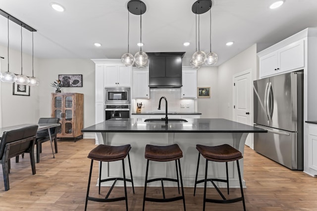 kitchen with decorative light fixtures, an island with sink, and appliances with stainless steel finishes