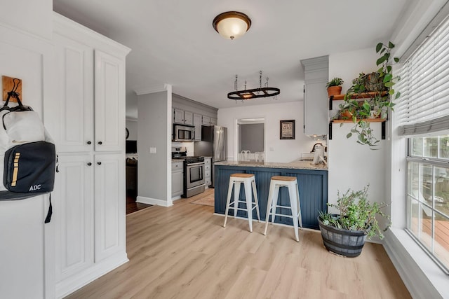 kitchen featuring a kitchen bar, sink, white cabinetry, stainless steel appliances, and light hardwood / wood-style floors