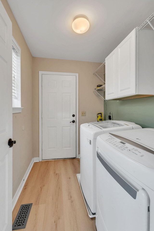 washroom with independent washer and dryer, cabinets, and light wood-type flooring