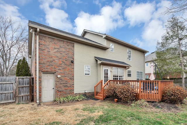 back of property featuring a wooden deck and a lawn