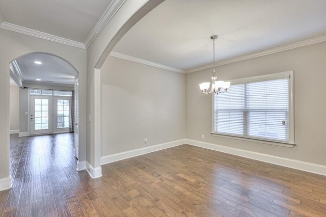 spare room with dark wood-type flooring, crown molding, and an inviting chandelier