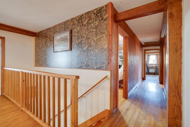 hallway featuring an upstairs landing, baseboards, and wood finished floors