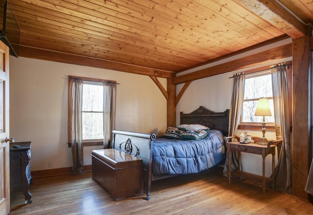 bedroom featuring beam ceiling, multiple windows, wood finished floors, and wood ceiling