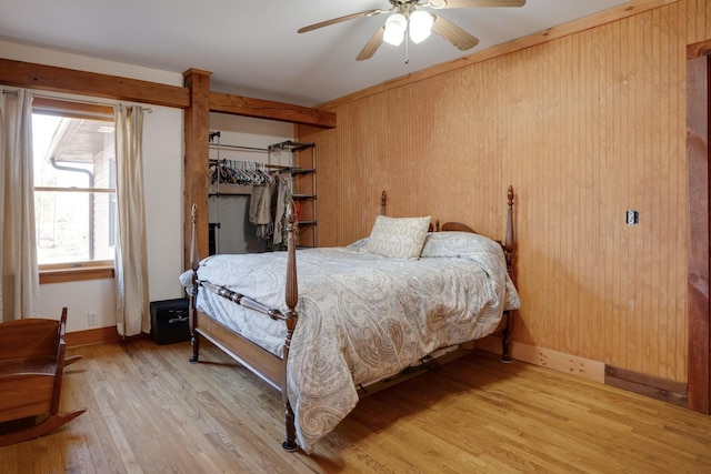 bedroom with wood walls, light wood-style floors, baseboards, and ceiling fan