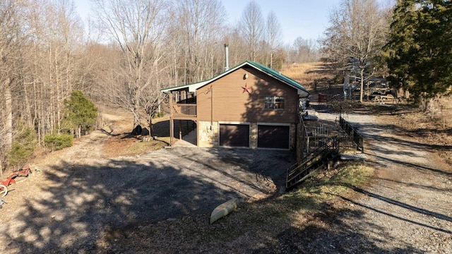view of side of property with a garage, aphalt driveway, and stone siding