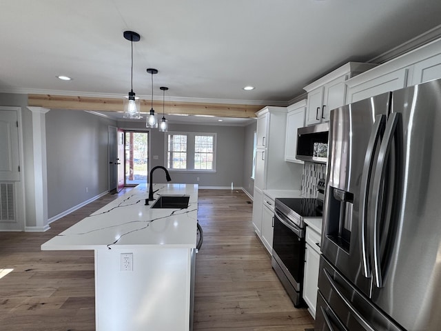 kitchen featuring appliances with stainless steel finishes, white cabinetry, sink, hanging light fixtures, and a center island with sink