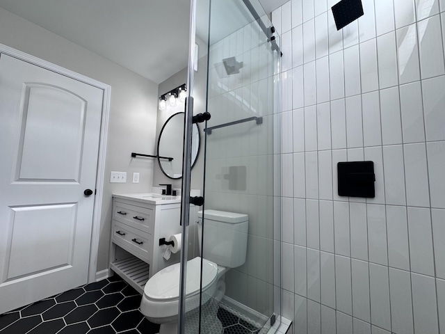 bathroom featuring tile patterned flooring, vanity, a tile shower, and toilet