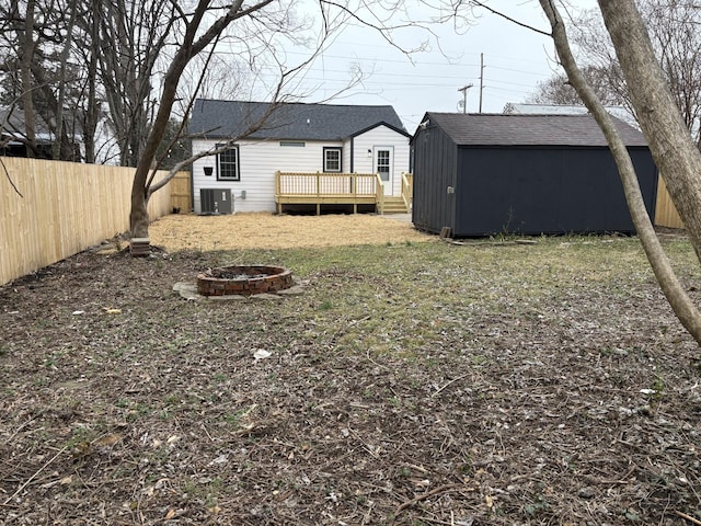 view of yard featuring a wooden deck, a shed, a fire pit, and cooling unit