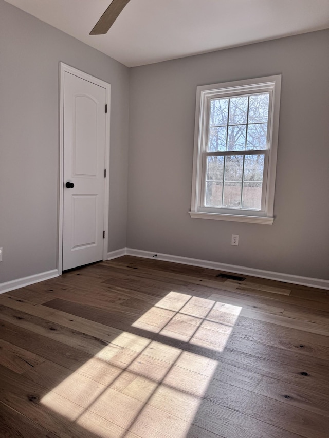 empty room with ceiling fan and dark hardwood / wood-style flooring