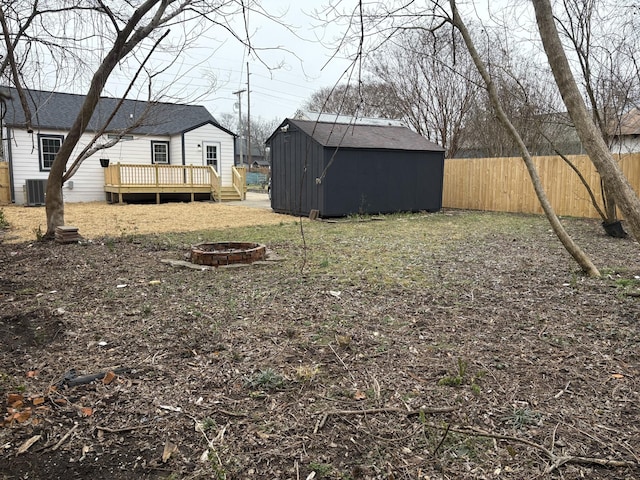 view of yard with a wooden deck, a fire pit, a storage shed, and central AC