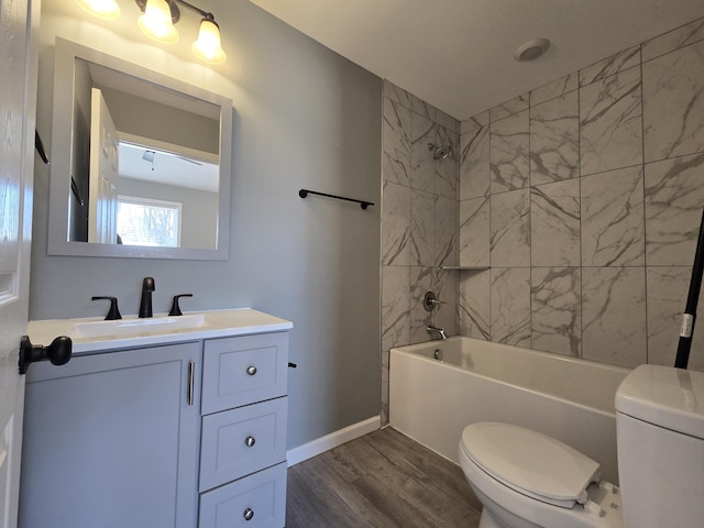 full bathroom with hardwood / wood-style flooring, tiled shower / bath, vanity, and toilet