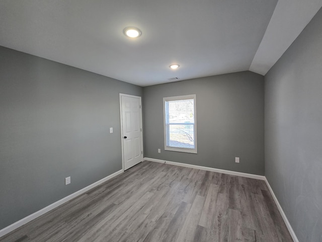 spare room featuring vaulted ceiling and light wood-type flooring