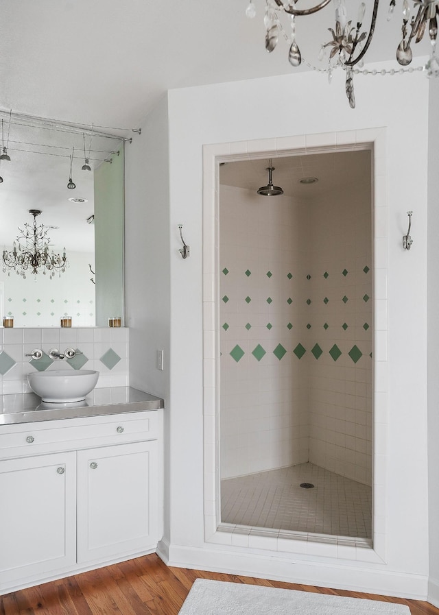 bathroom with tiled shower, vanity, and hardwood / wood-style floors