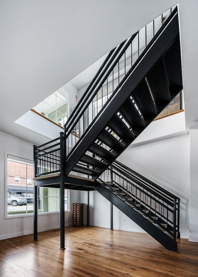 stairway with hardwood / wood-style flooring and a high ceiling