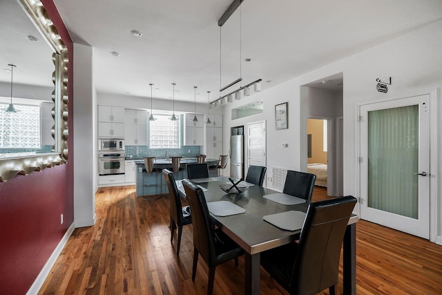 dining room with hardwood / wood-style floors and track lighting