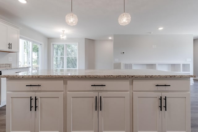 kitchen with hanging light fixtures, a chandelier, white cabinets, and light stone counters