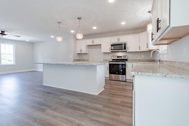 kitchen featuring sink, hanging light fixtures, stainless steel appliances, white cabinets, and a kitchen island