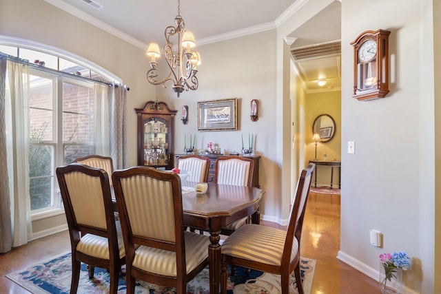 dining space featuring crown molding, an inviting chandelier, and light wood-type flooring