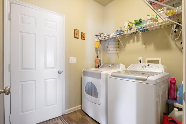 laundry room featuring washing machine and clothes dryer and dark tile patterned flooring