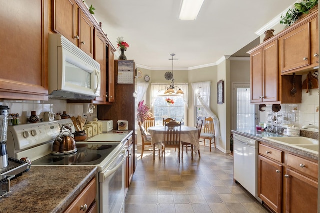 kitchen featuring pendant lighting, tasteful backsplash, sink, ornamental molding, and white appliances