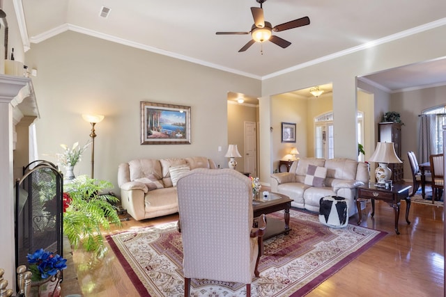 living room with lofted ceiling, hardwood / wood-style flooring, ornamental molding, and ceiling fan