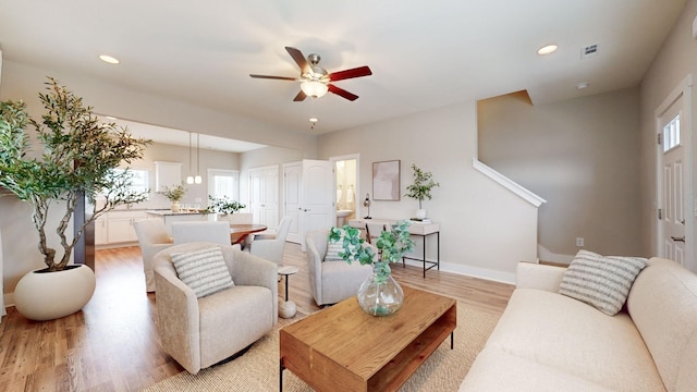 living room with a wealth of natural light, ceiling fan, and light wood-type flooring