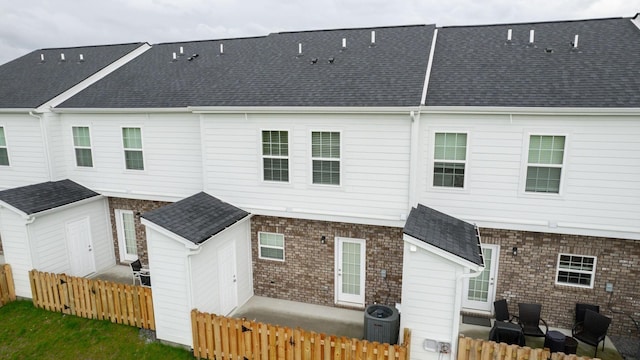 back of house featuring central AC and a shed