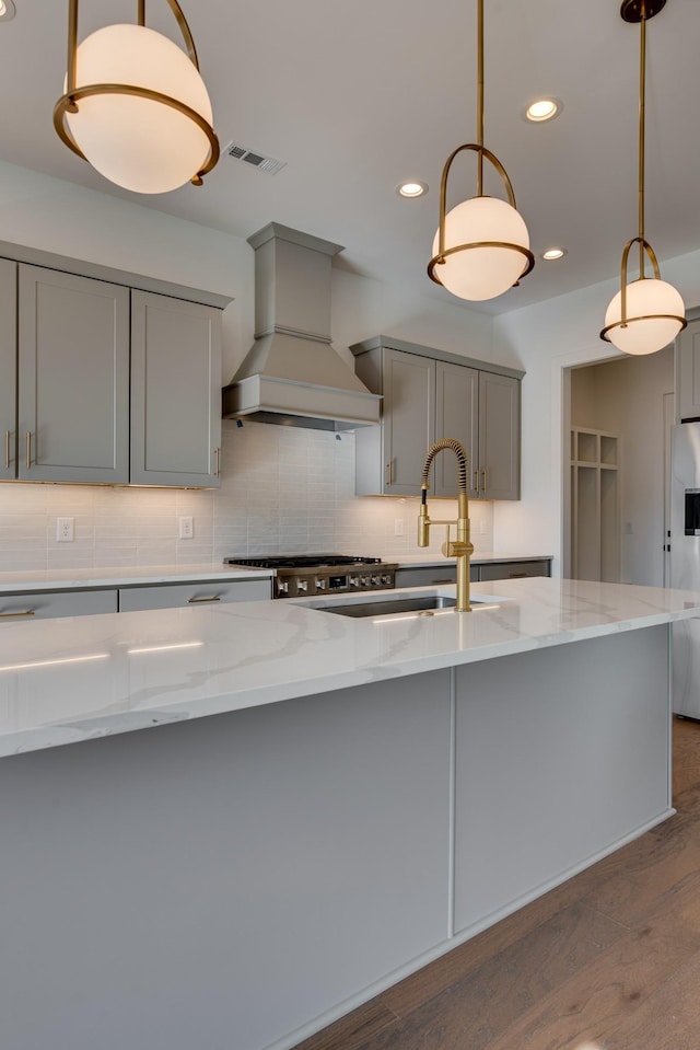 kitchen featuring gray cabinets, tasteful backsplash, stainless steel refrigerator with ice dispenser, light stone countertops, and custom range hood