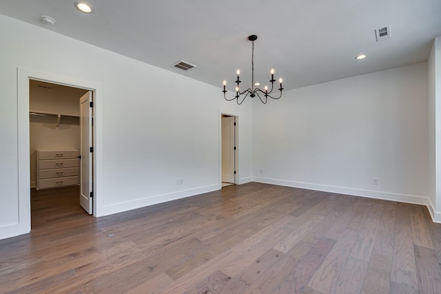 unfurnished room with hardwood / wood-style floors and an inviting chandelier