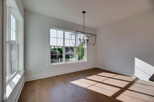 unfurnished dining area with a chandelier and hardwood / wood-style floors