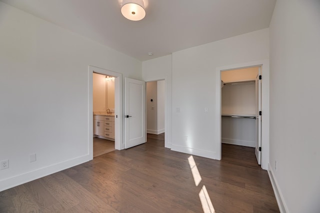 unfurnished bedroom with sink, ensuite bath, dark hardwood / wood-style floors, a spacious closet, and a closet