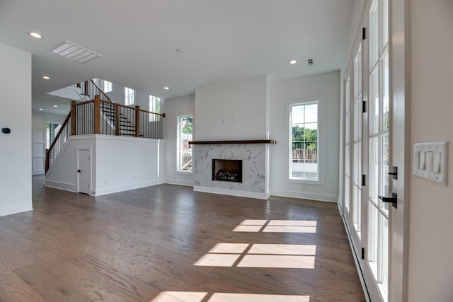 unfurnished living room with plenty of natural light, dark hardwood / wood-style floors, and a high end fireplace