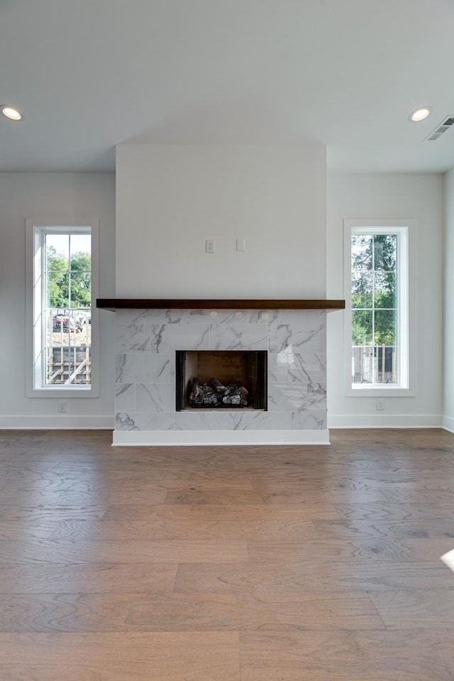 unfurnished living room with hardwood / wood-style flooring, a high end fireplace, and a wealth of natural light